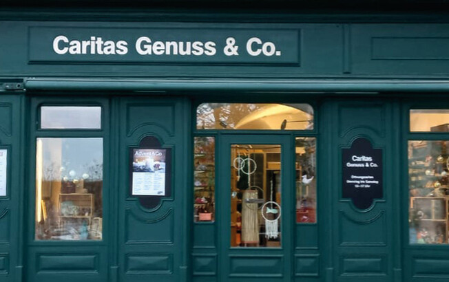 Aussenansicht der grünen Fassade aus Holz des Shops Caritas Genuss & Co.